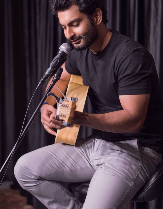 Sagar Raina performing with an acoustic guitar at an event
